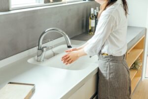 お弁当作りの前に石けんと流水で手を洗う様子