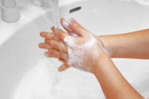 スポーツ施設の洗面所で石けんと流水を使って手を洗う利用者