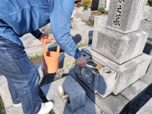 周囲に配慮しながら墓所を掃除する家族