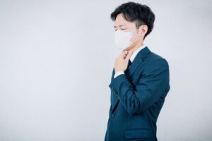 人が集まる室内でマスクを着用して咳エチケットを行う人