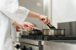 厨房で加熱調理を行うスタッフ